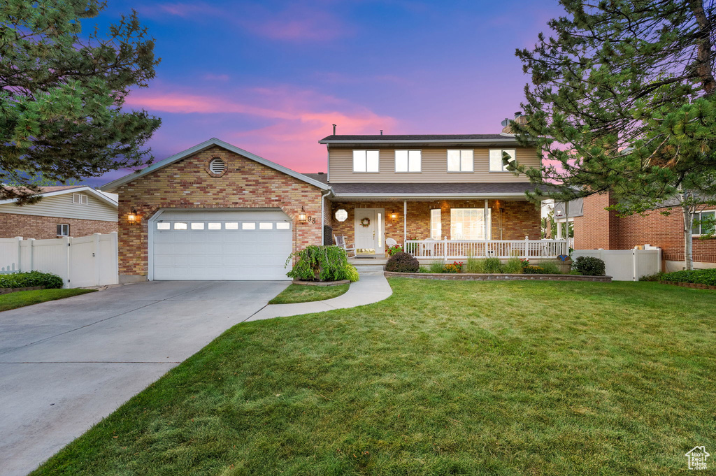 Traditional home with a porch, an attached garage, concrete driveway, and brick siding