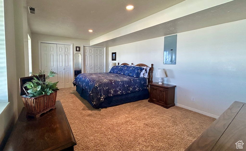 Carpeted bedroom featuring electric panel, two closets, and recessed lighting