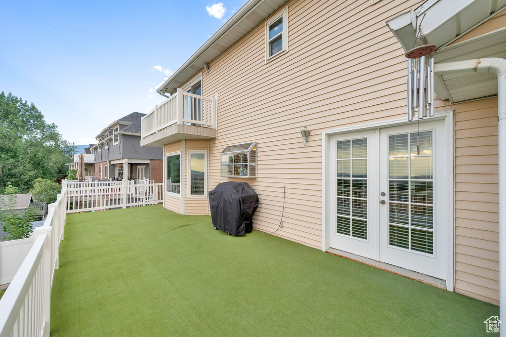 Fenced backyard featuring a balcony and french doors