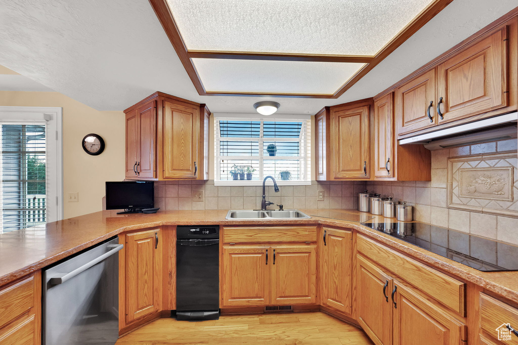 Kitchen with stainless steel dishwasher, black electric stovetop, plenty of natural light, light wood-style flooring, and a textured ceiling