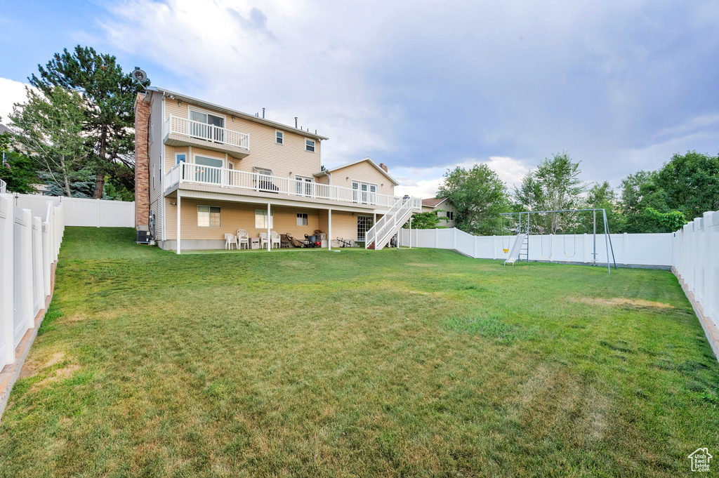 Rear view of house featuring a fenced backyard, stairway, a chimney, and a playground