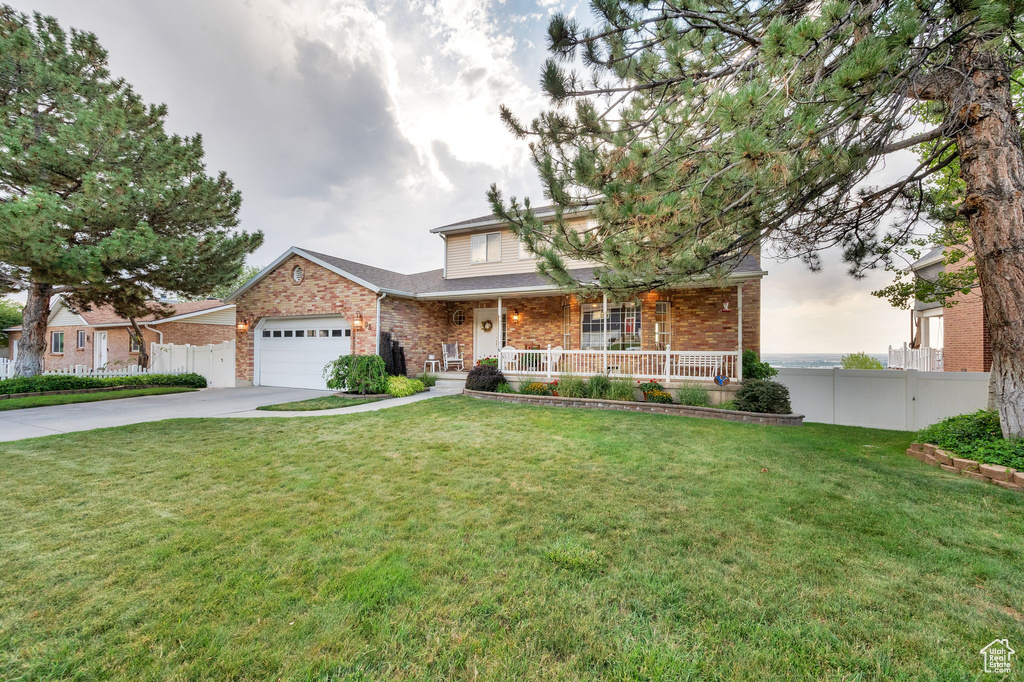 Traditional-style home featuring covered porch, brick siding, driveway, and an attached garage