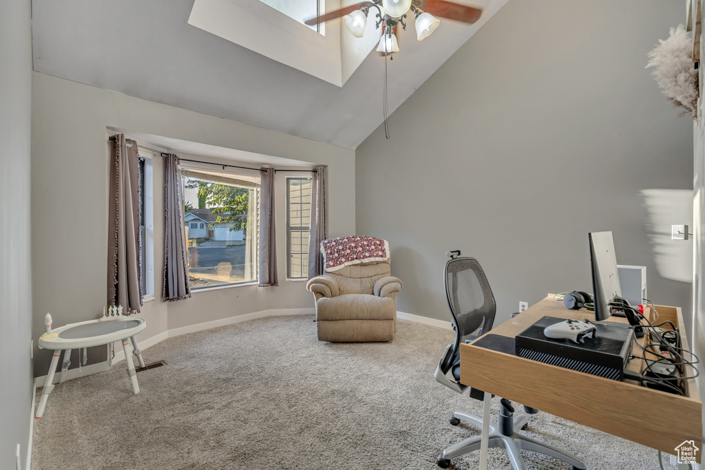 Carpeted office featuring a ceiling fan, high vaulted ceiling, and a skylight