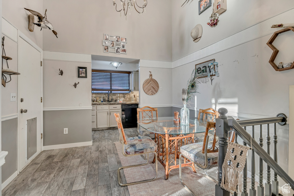 Dining room with light wood finished floors, a towering ceiling, and a chandelier