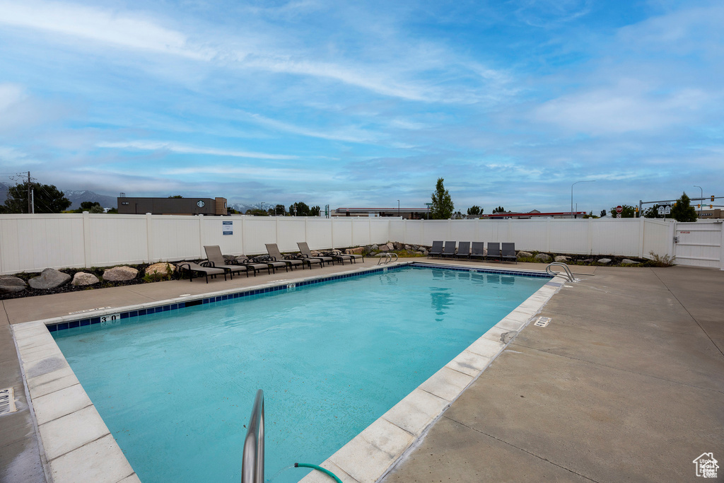 Community pool with a patio and a fenced backyard