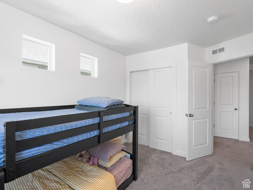 Carpeted bedroom with a closet and a textured ceiling