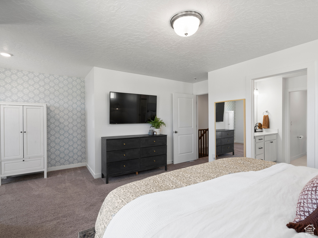 Bedroom featuring carpet flooring, wallpapered walls, a textured ceiling, and connected bathroom