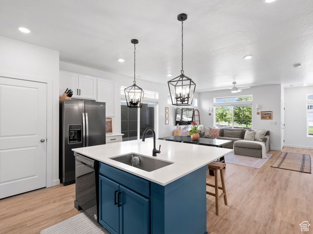 Kitchen with dishwasher, blue cabinets, refrigerator with ice dispenser, light wood-style flooring, and white cabinetry