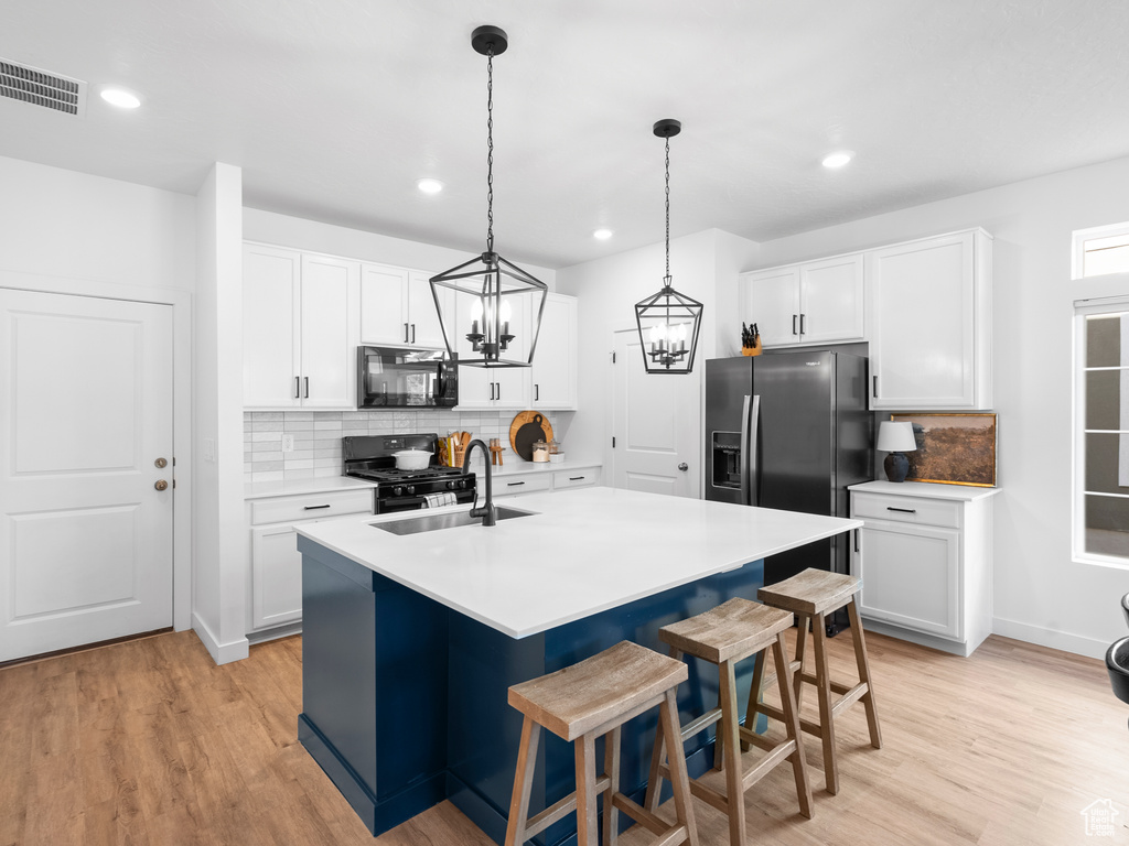 Kitchen featuring black appliances, tasteful backsplash, light wood-style flooring, and recessed lighting