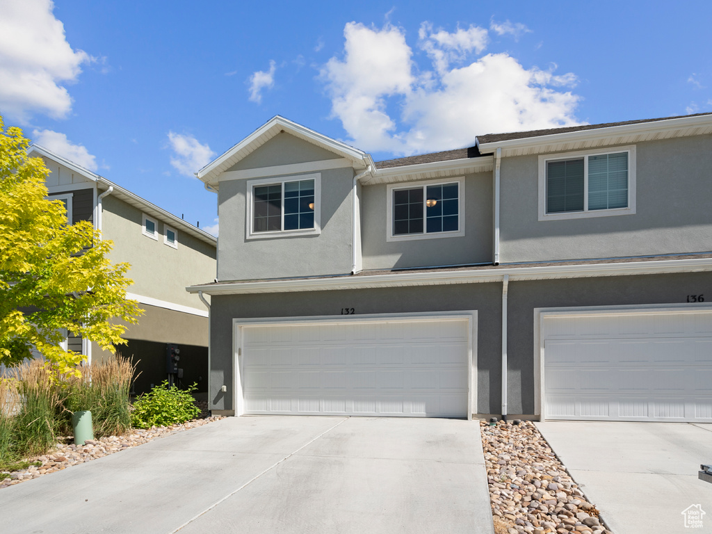 Multi unit property with an attached garage, concrete driveway, and stucco siding