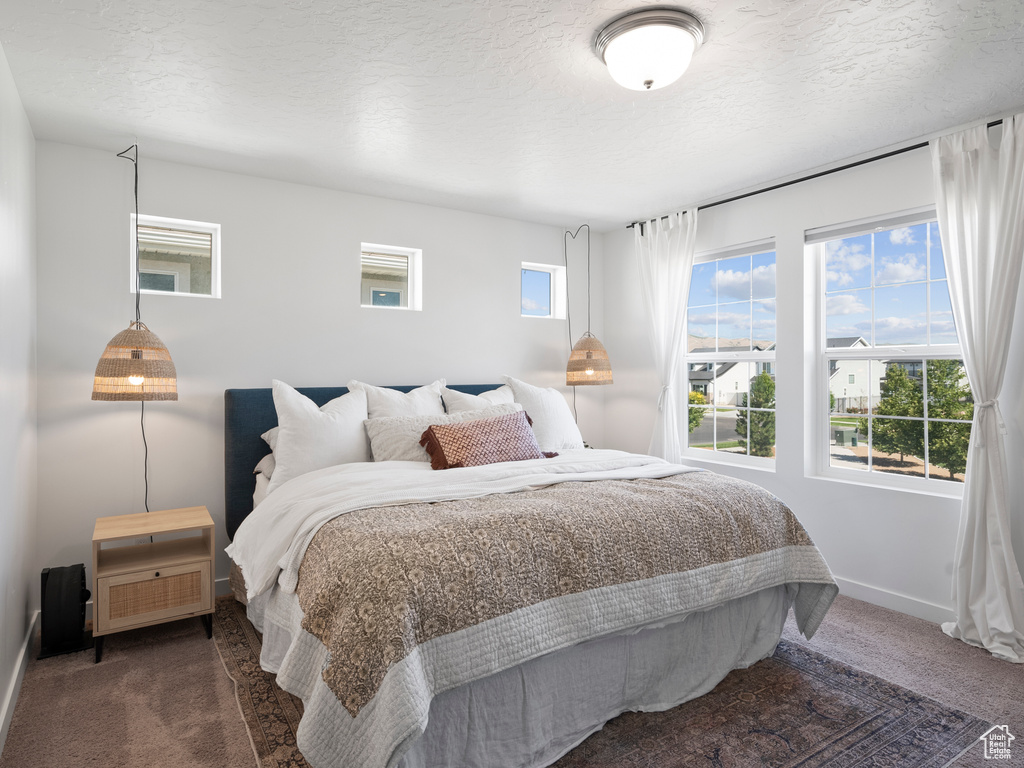 Carpeted bedroom featuring baseboards and a textured ceiling