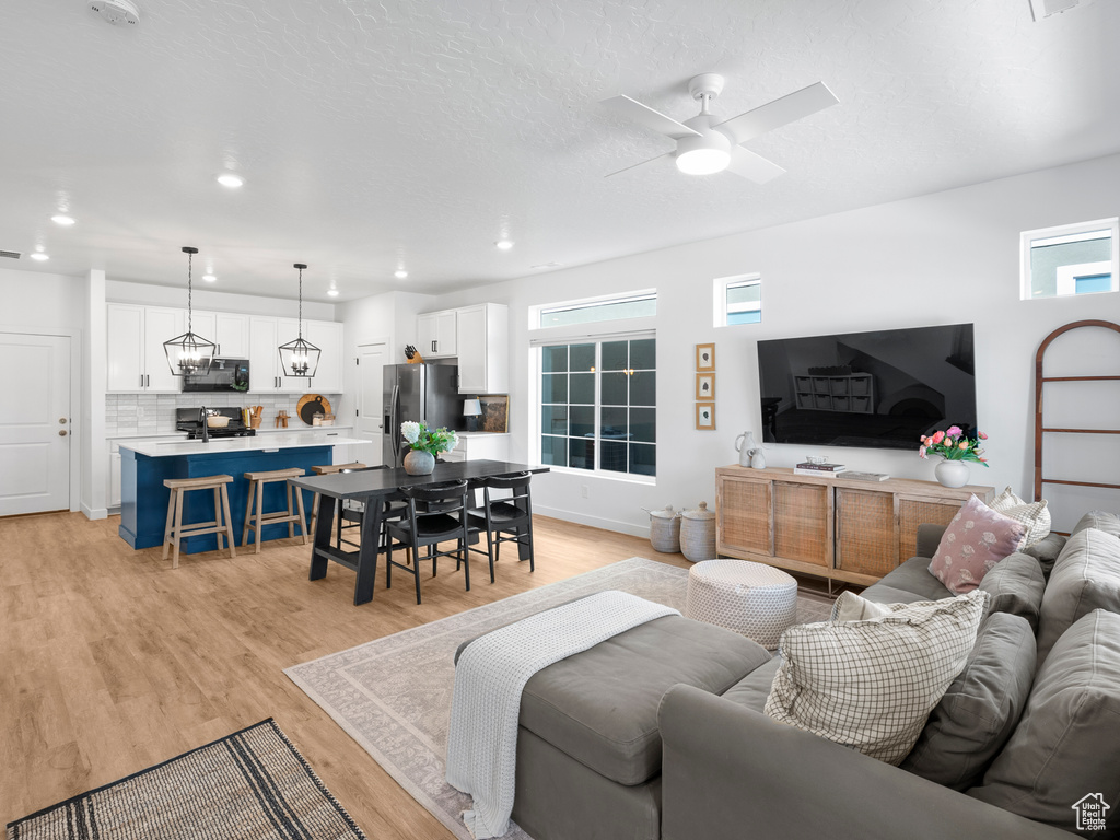 Living area with a ceiling fan, recessed lighting, and light wood-style floors