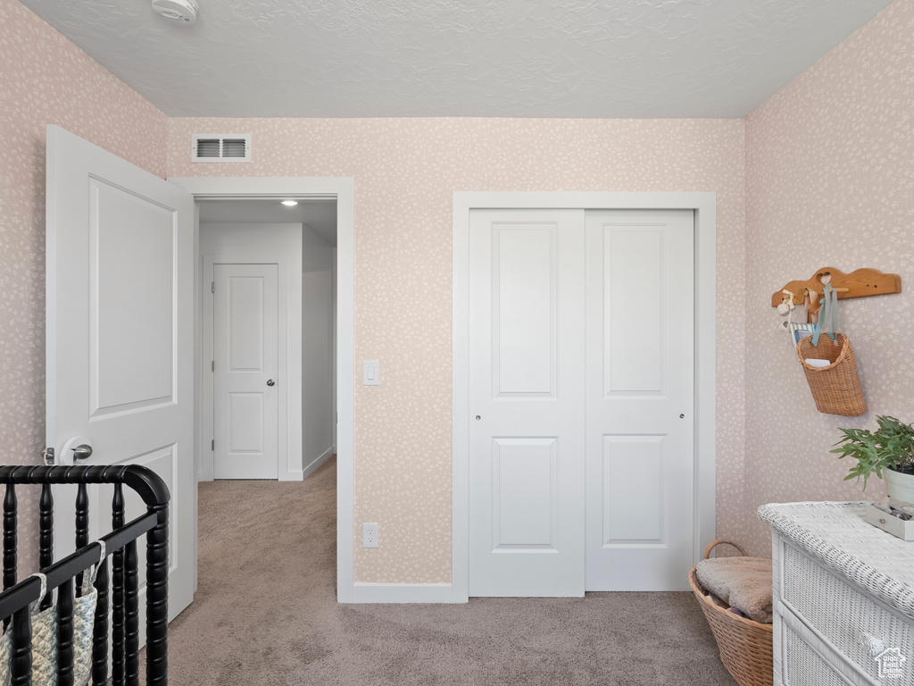 Carpeted bedroom with wallpapered walls and a closet