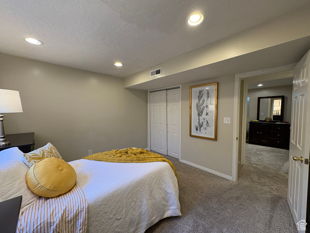 Carpeted bedroom featuring a textured ceiling, recessed lighting, and a closet