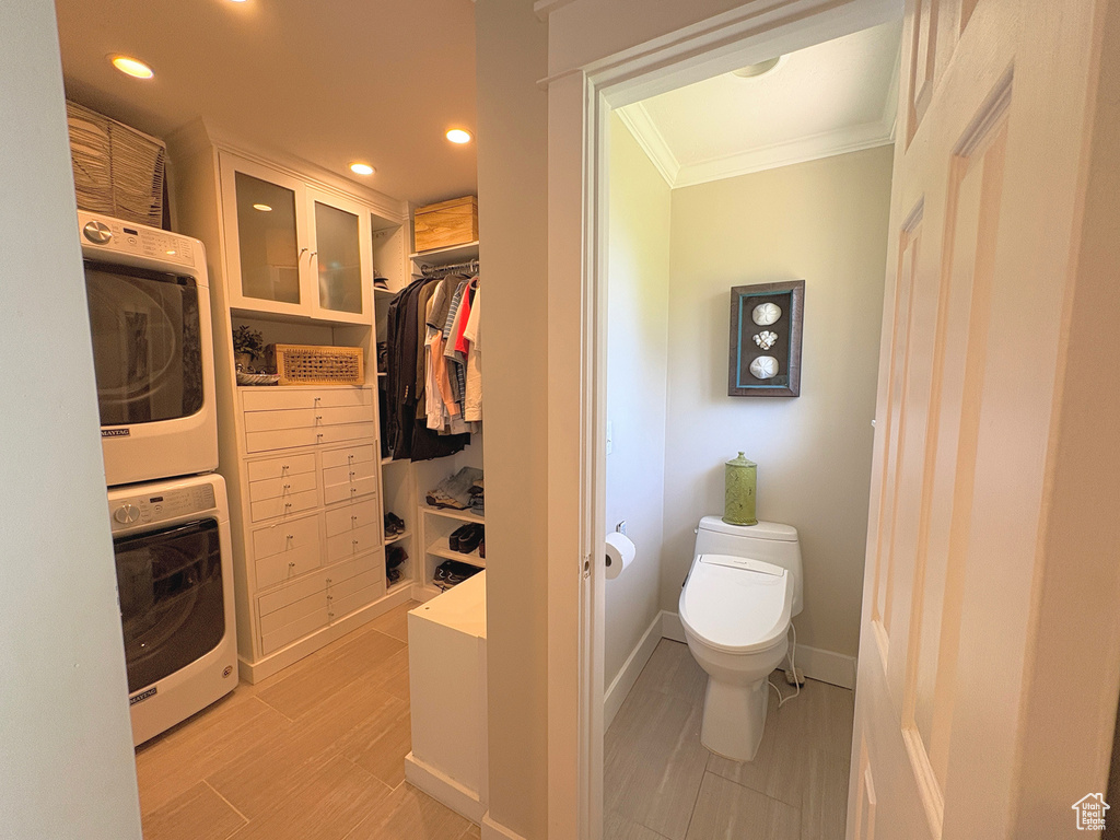Bathroom featuring crown molding, estacked washer and dryer, recessed lighting, wood finished floors, and a spacious closet