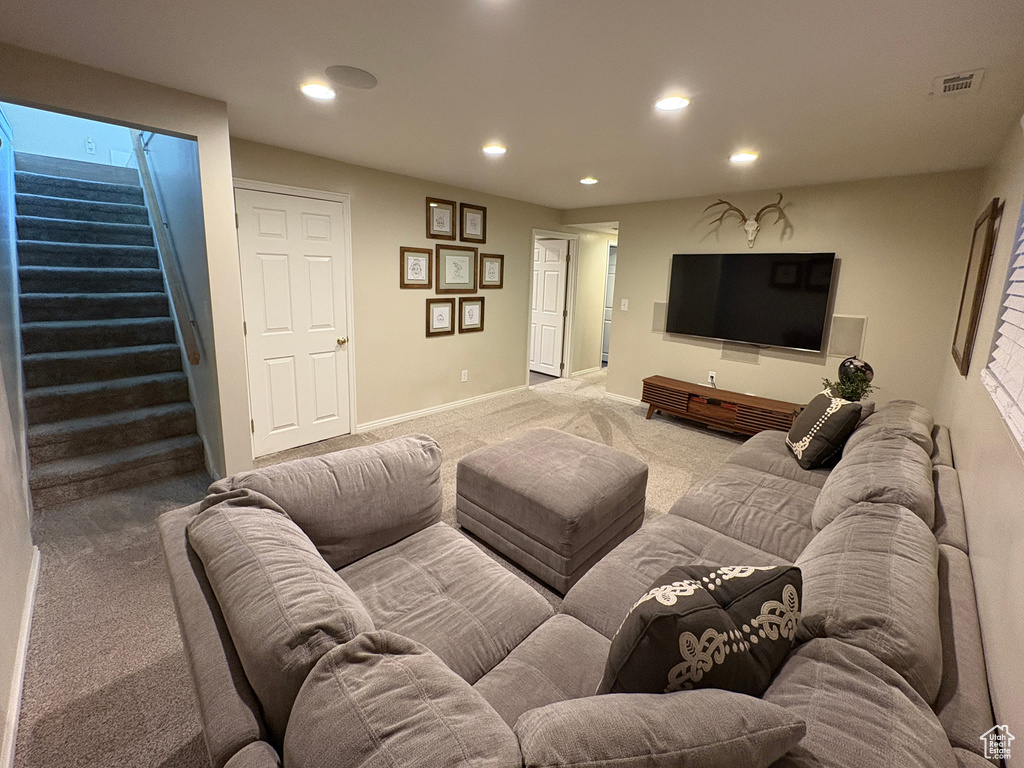 Living room with light colored carpet, recessed lighting, and stairway