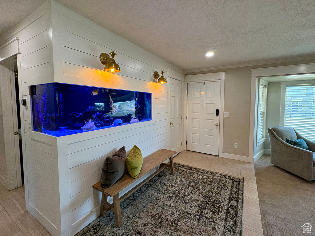 Entrance foyer with ornamental molding, a textured ceiling, light wood-style flooring, and recessed lighting