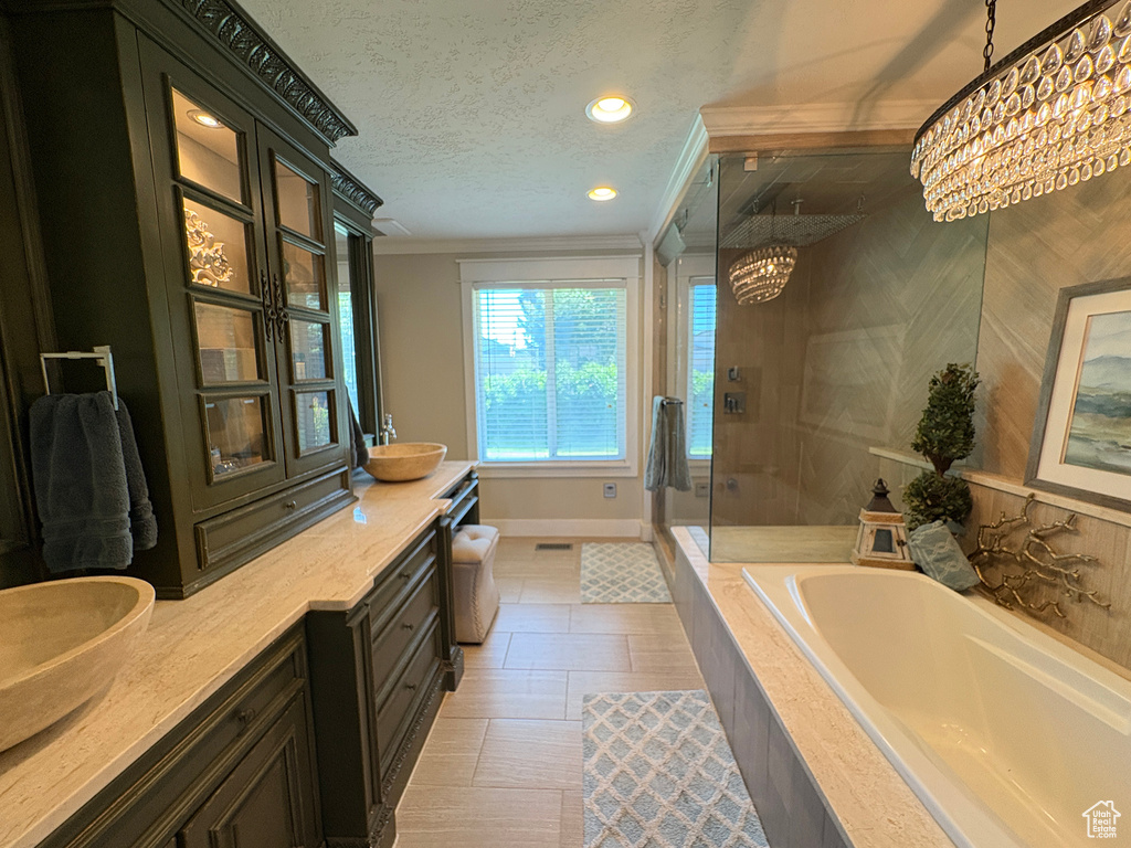 Bathroom with a chandelier, ornamental molding, a shower stall, a bath, and double vanity