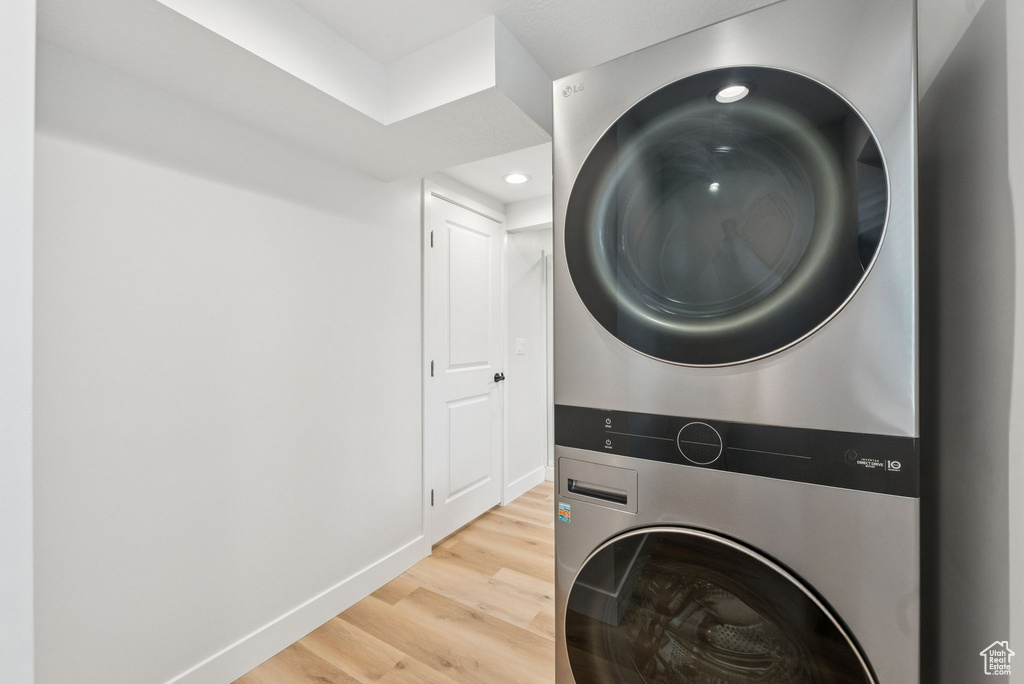 Laundry area with estacked washer and dryer, light wood-style floors, and recessed lighting