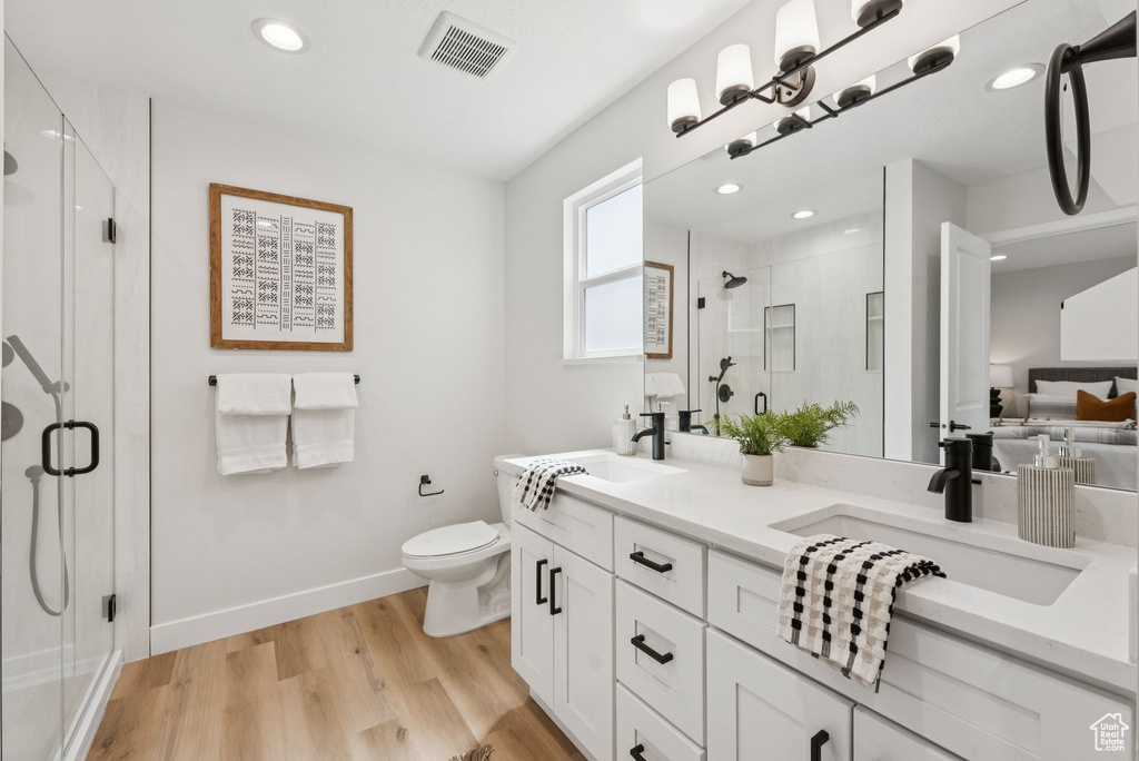 Full bath featuring double vanity, a stall shower, wood finished floors, and recessed lighting
