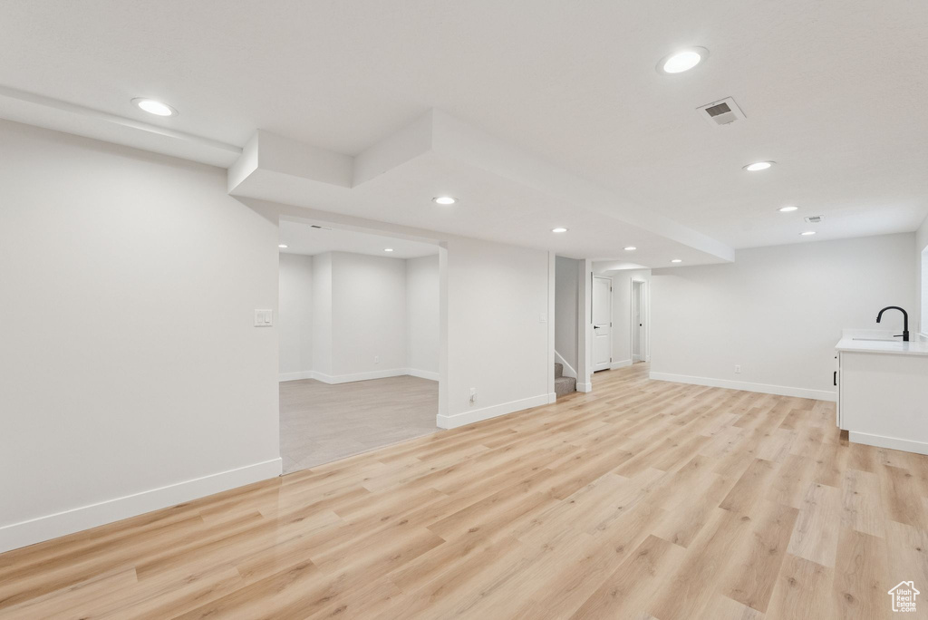 Finished basement with recessed lighting, stairway, and light wood-style floors