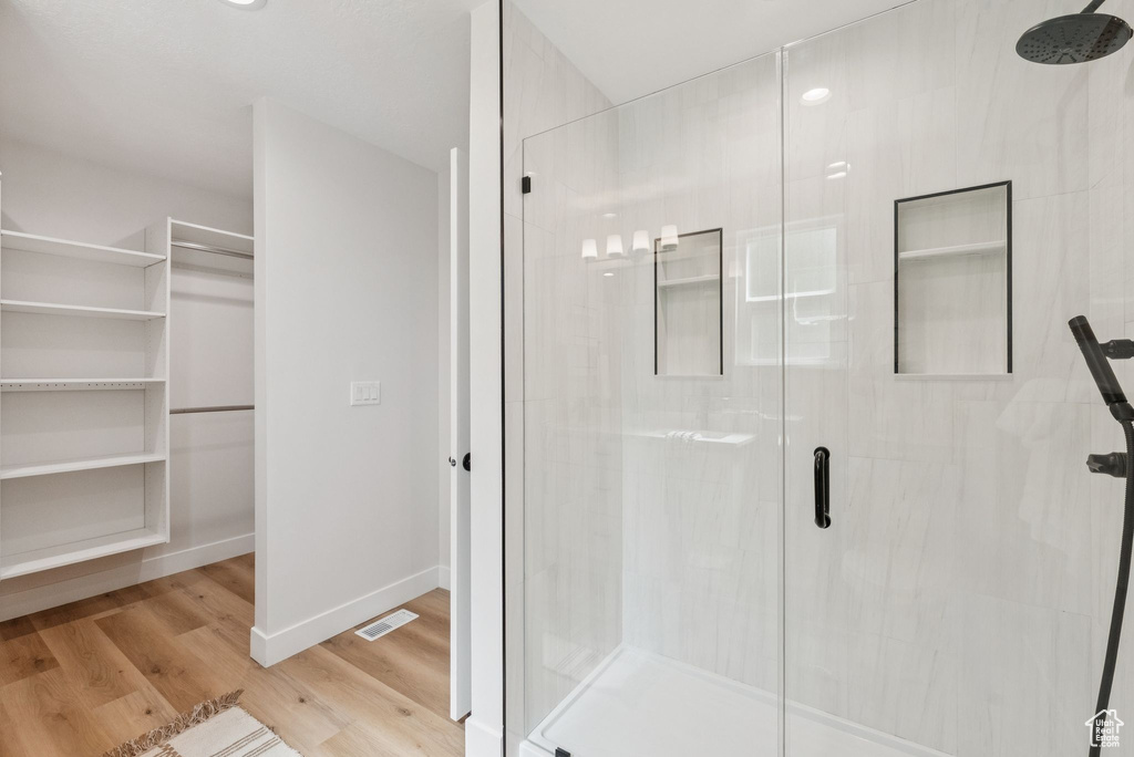 Full bathroom with a stall shower, wood finished floors, and a walk in closet