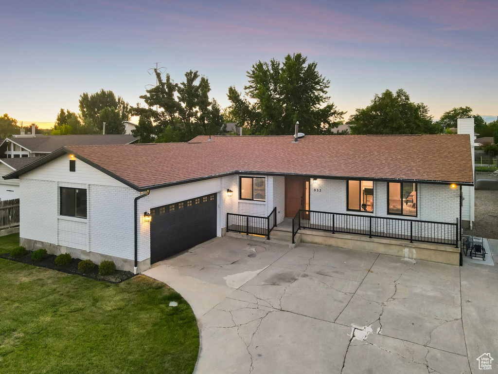 View of front of property featuring brick siding, a garage, a porch, and concrete driveway