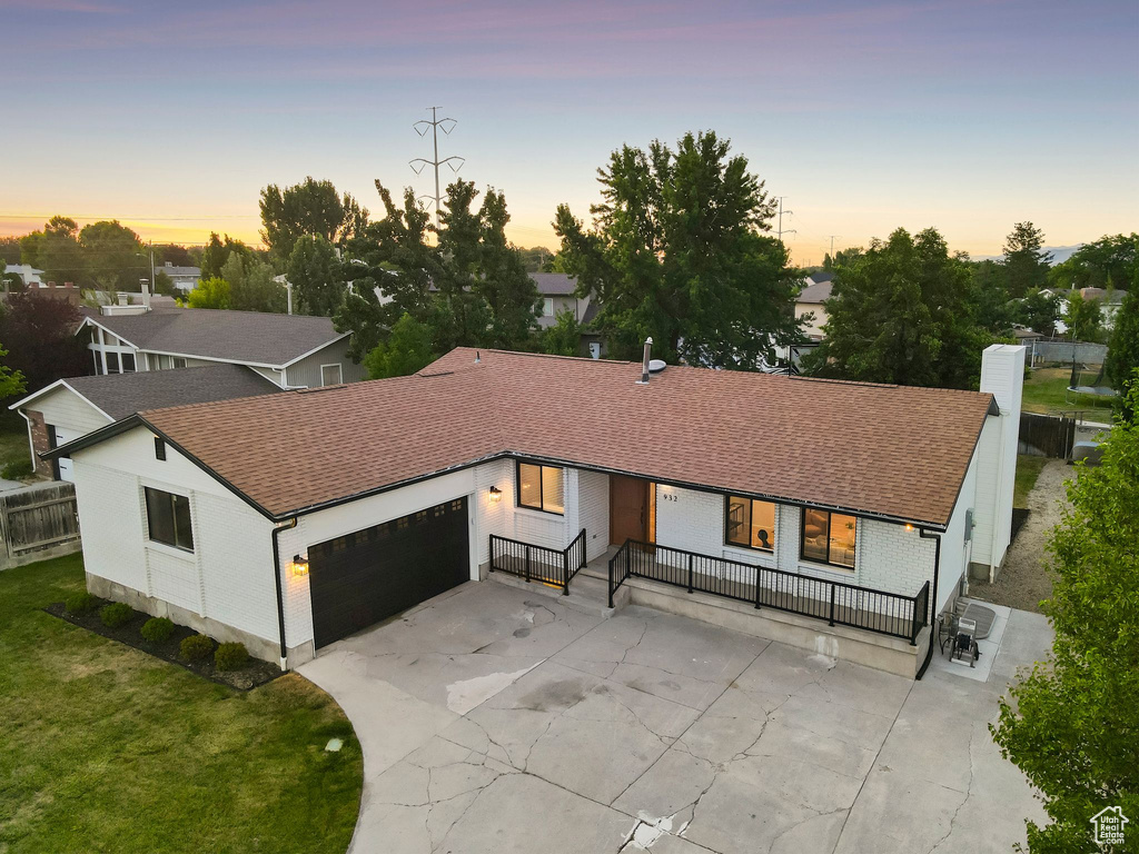 View of front of property featuring an attached garage, a shingled roof, concrete driveway, and a chimney