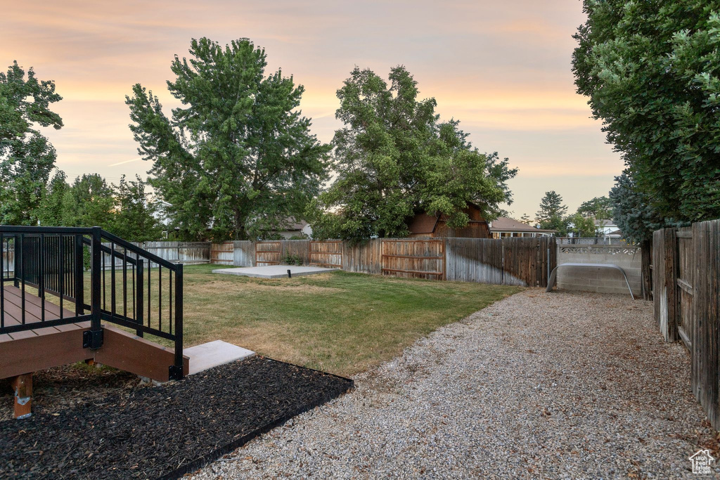 Yard at dusk with a fenced backyard and a deck