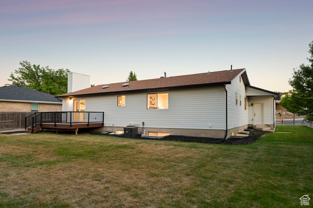 Back of house at dusk featuring a wooden deck, entry steps, and a chimney