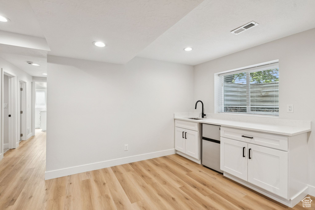 Bar featuring light wood finished floors, fridge, and recessed lighting