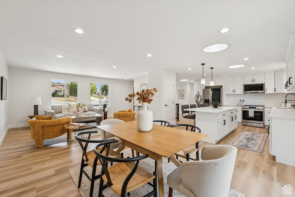 Dining area with light wood finished floors and recessed lighting