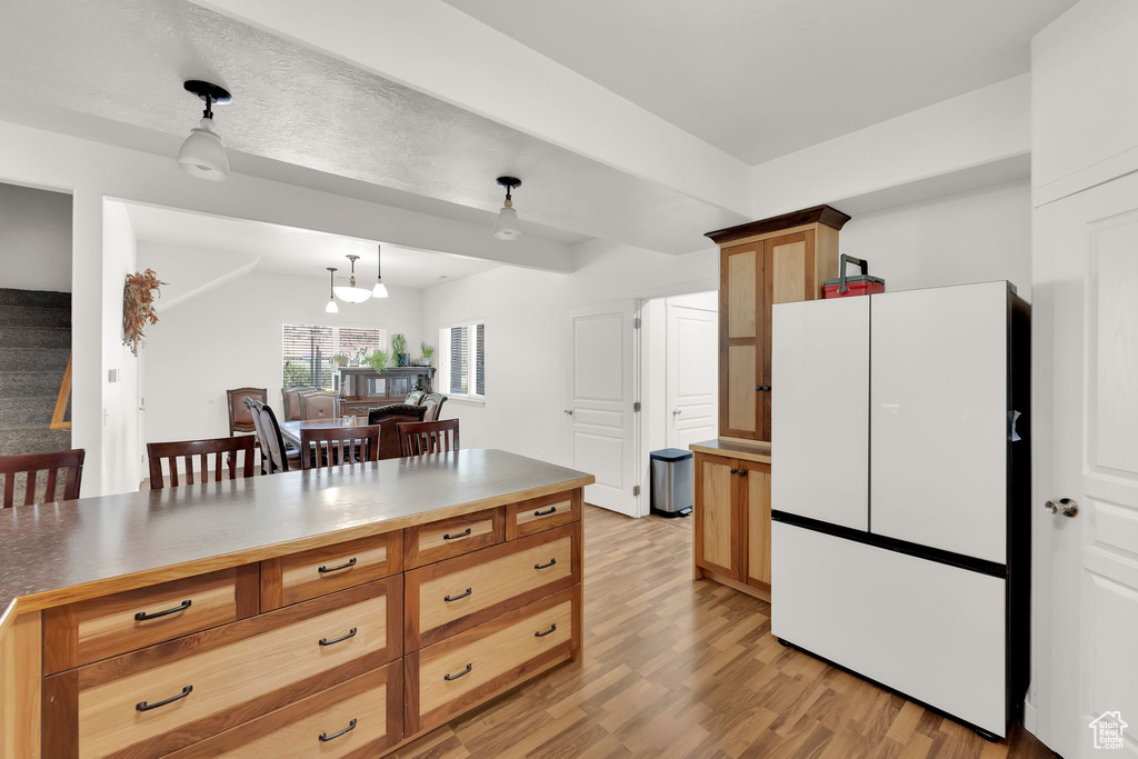 Kitchen featuring freestanding refrigerator, light wood finished floors, and decorative light fixtures