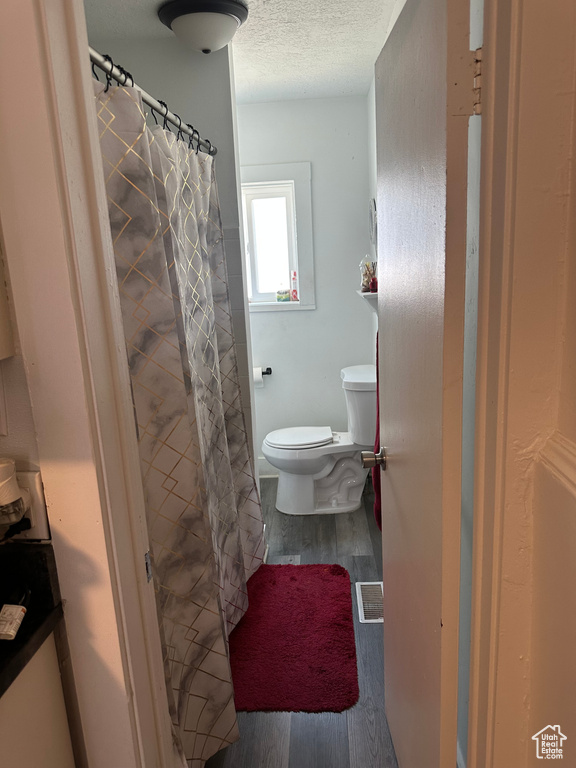 Bathroom with wood finished floors, a textured ceiling, and a shower with curtain