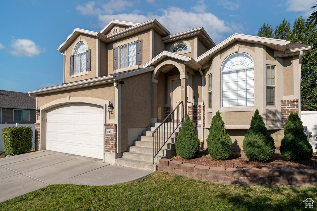 View of front of home featuring a garage, concrete driveway, stucco siding, and brick siding