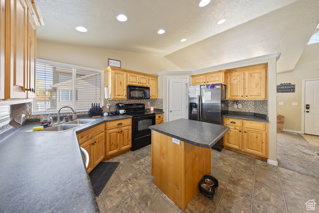 Kitchen featuring black appliances, vaulted ceiling, tasteful backsplash, dark countertops, and a center island