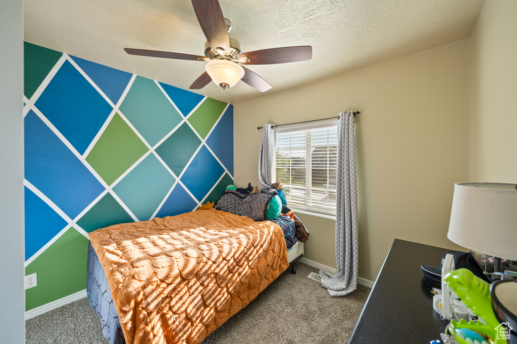 Bedroom with carpet flooring, ceiling fan, and a textured ceiling