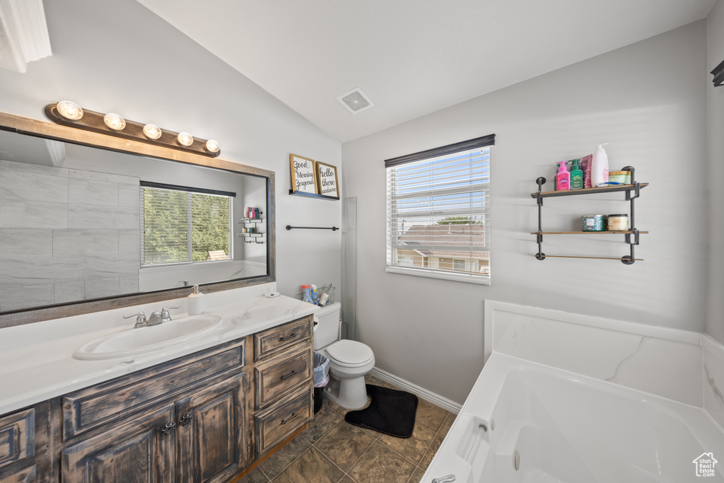Full bathroom featuring vaulted ceiling, a garden tub, and vanity