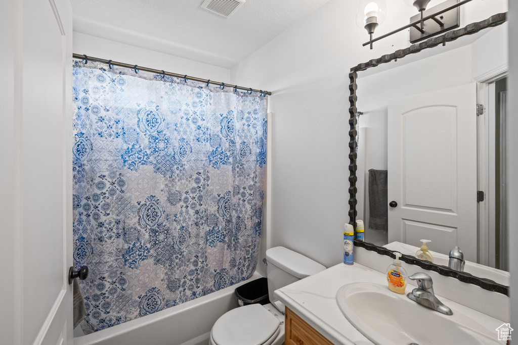Bathroom featuring vanity and shower / bathtub combination with curtain