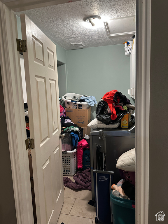 Washroom featuring independent washer and dryer, tile patterned floors, and a textured ceiling