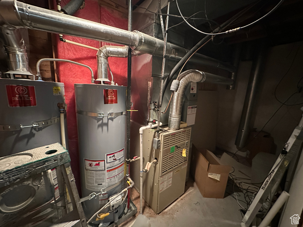 Utility room featuring strapped water heater