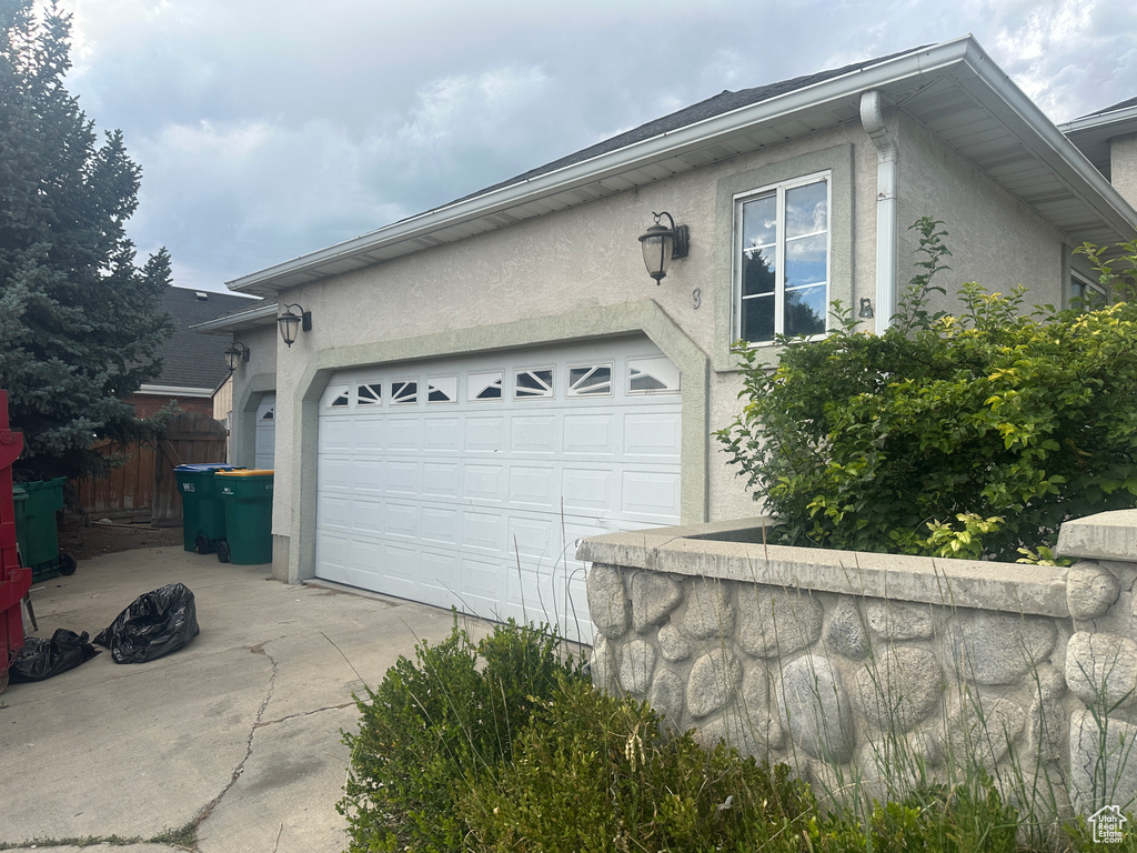 View of home's exterior featuring stucco siding, concrete driveway, and an attached garage
