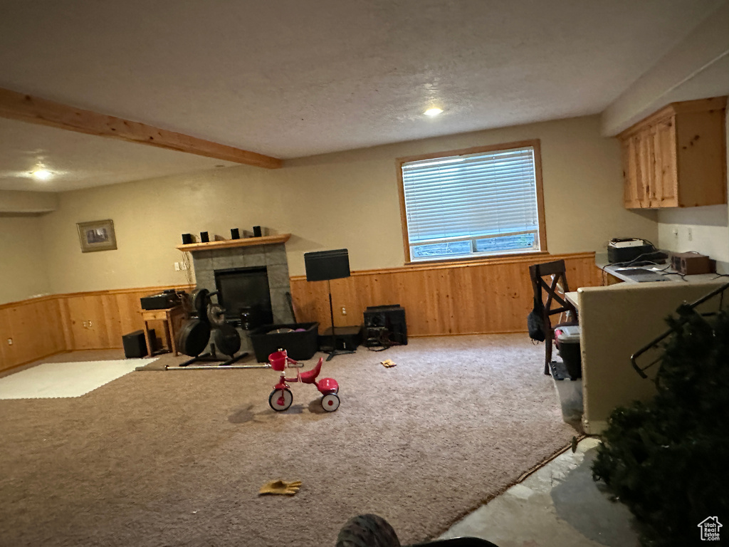Recreation room featuring wainscoting, wooden walls, carpet flooring, and a tiled fireplace
