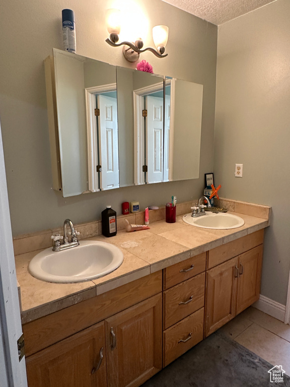 Full bathroom with double vanity, a textured ceiling, and tile patterned floors