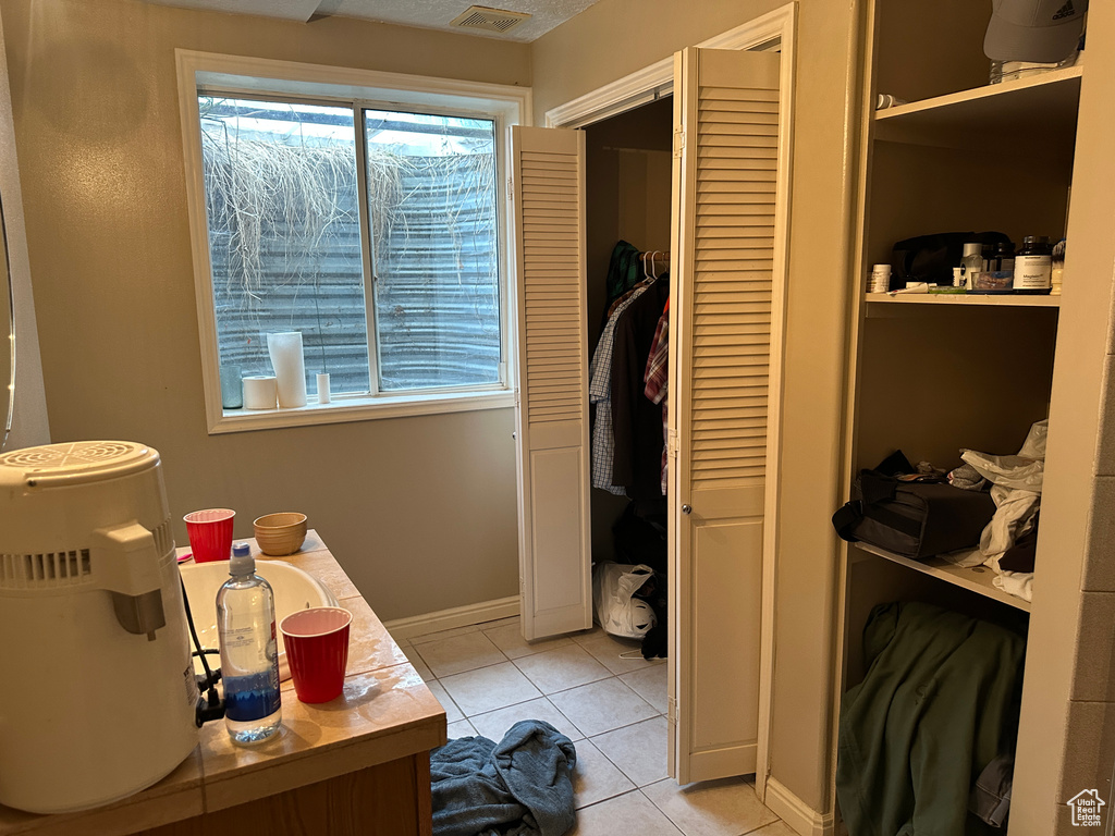 Bathroom featuring a closet, tile patterned floors, plenty of natural light, and vanity