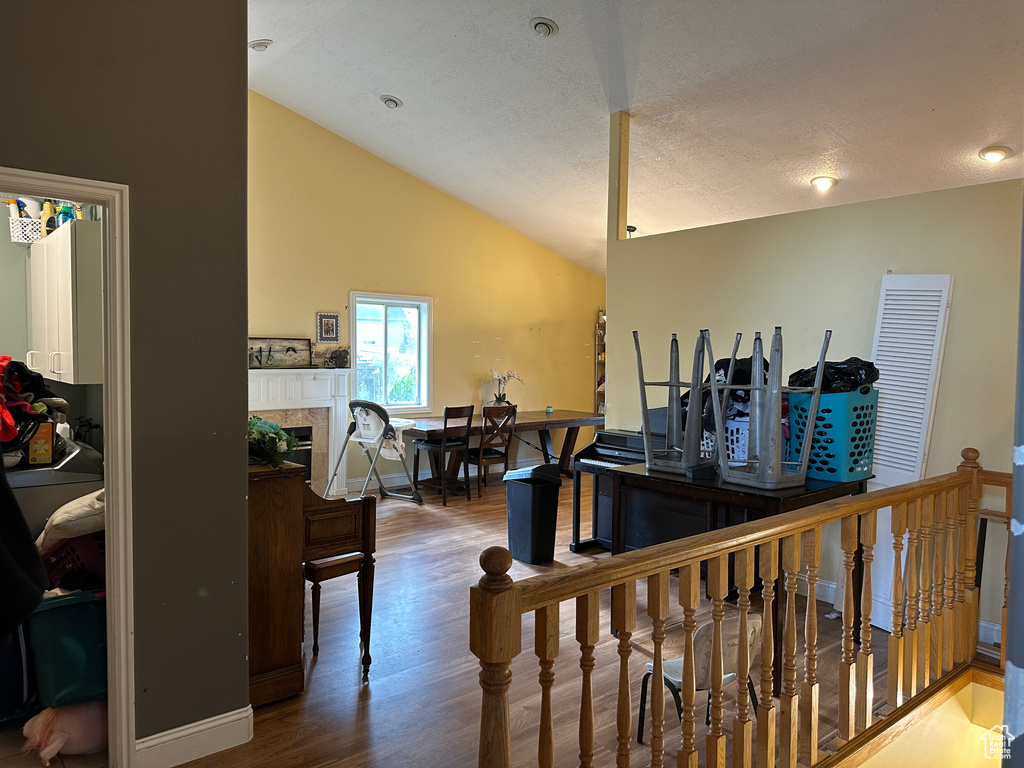 Corridor featuring wood finished floors, high vaulted ceiling, and an upstairs landing
