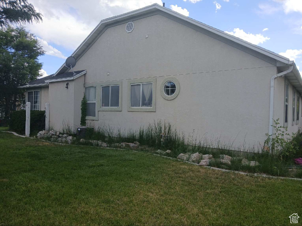 View of side of property with a lawn and stucco siding