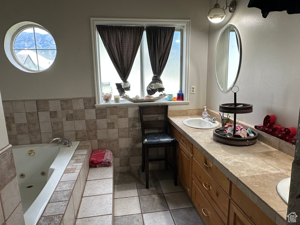 Bathroom with healthy amount of natural light, double vanity, a whirlpool tub, and tile patterned floors