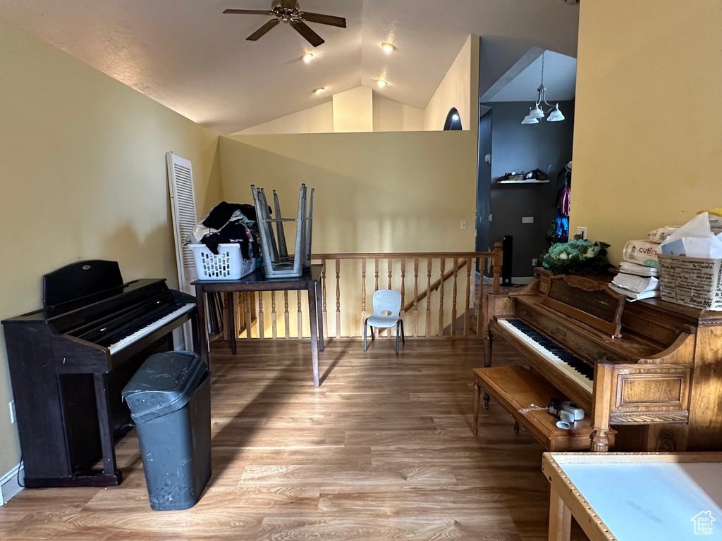 Living area with ceiling fan, wood finished floors, lofted ceiling, and an upstairs landing