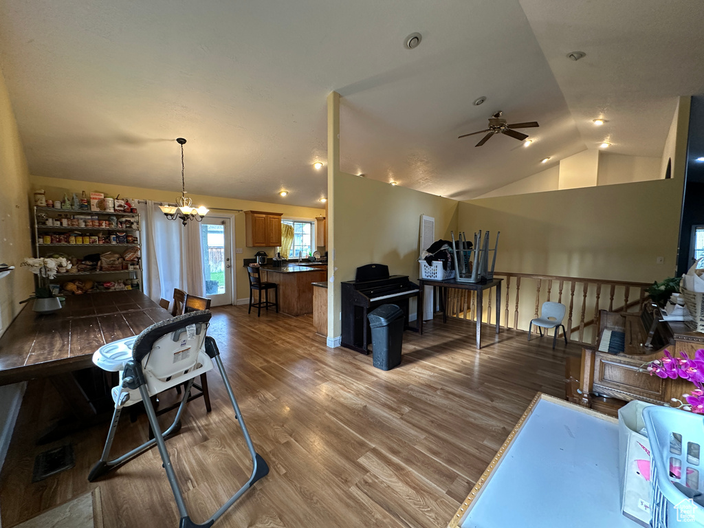 Dining room with lofted ceiling, a ceiling fan, a chandelier, and wood finished floors